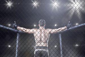 UFC fighter in cage with his arms raised in the air.