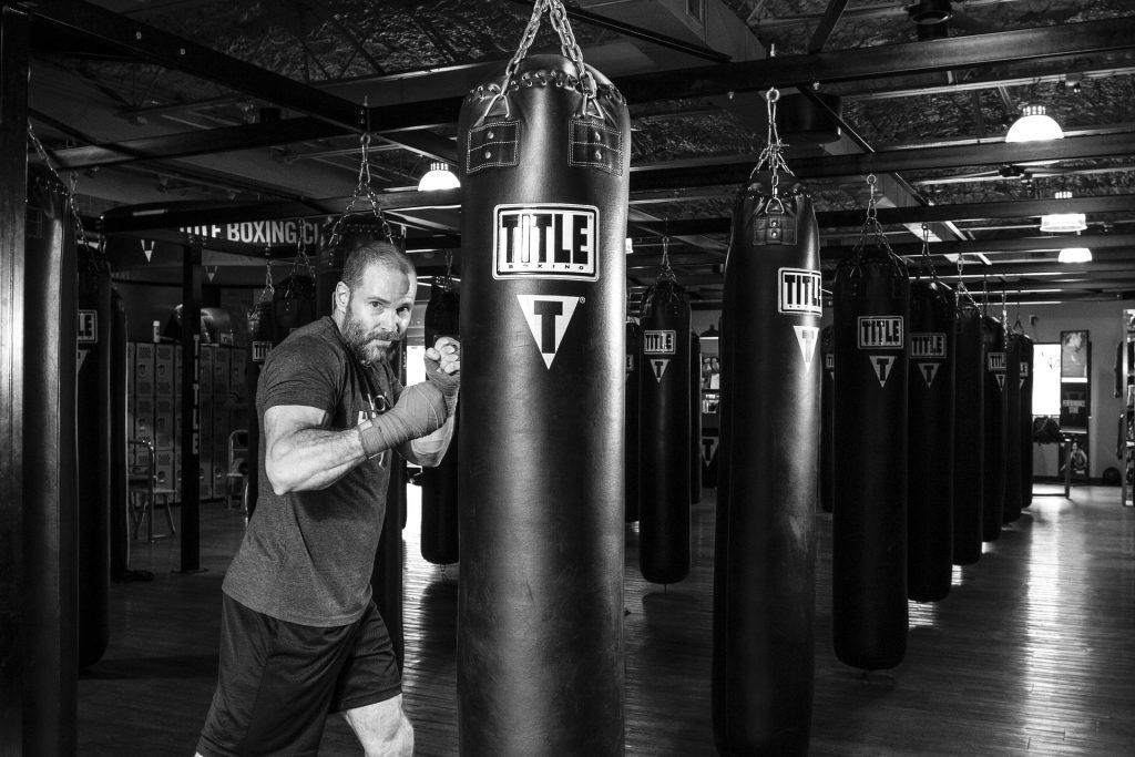 A man punching a punching bag in a gym.