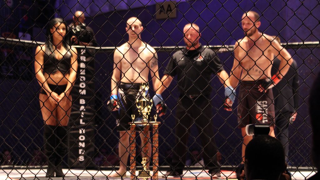 A group of mma fighters standing in a cage.