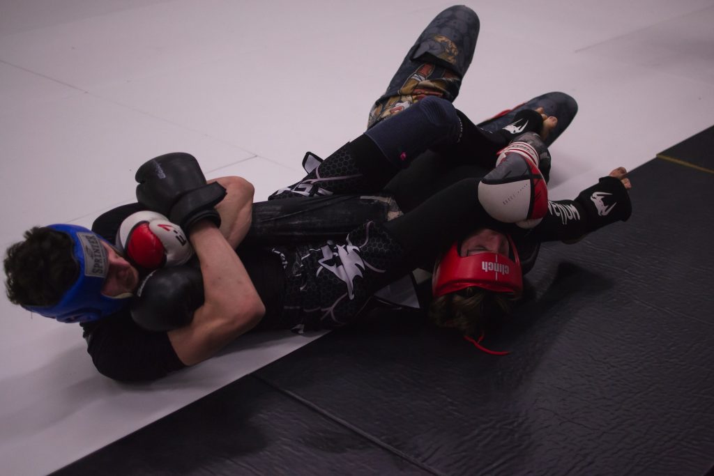 A man is laying on the ground in a boxing ring.