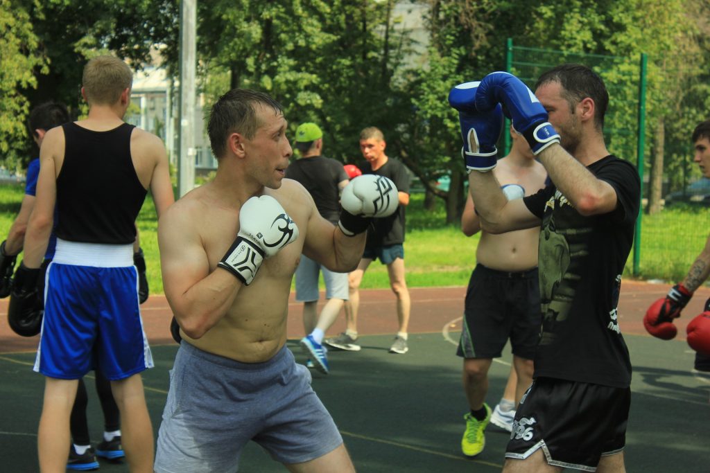 A group of men practicing boxing in a park.