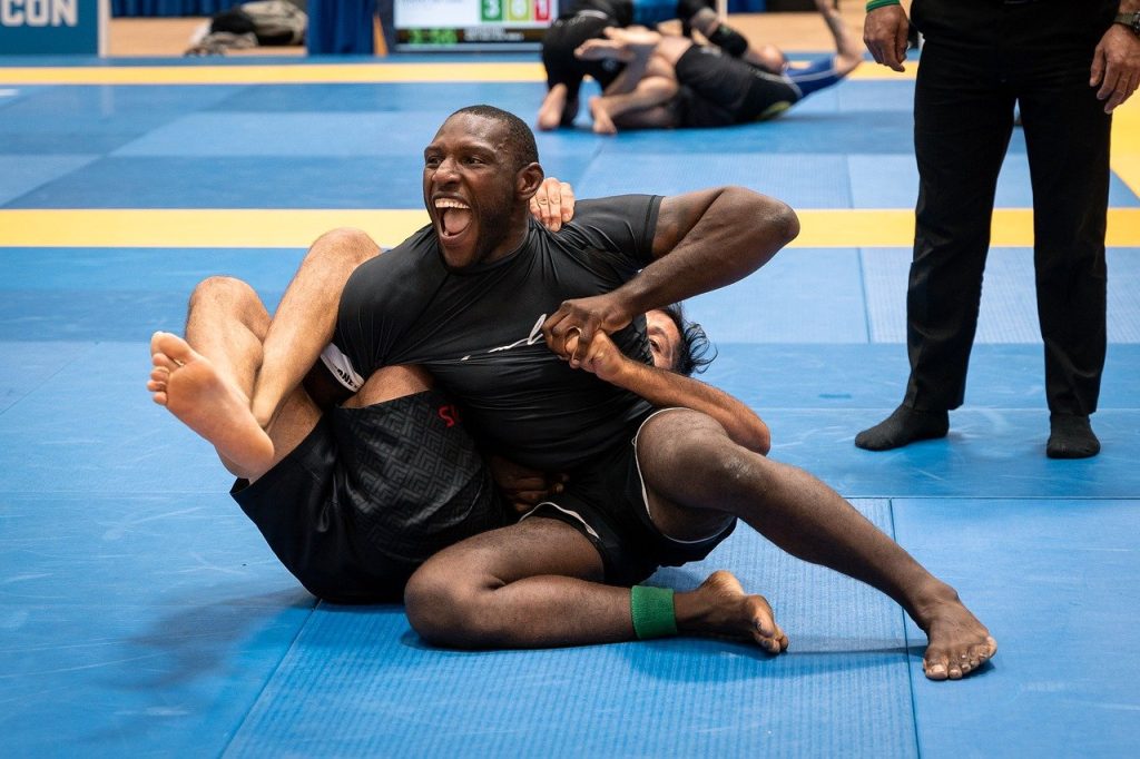 A man is wrestling with another man in a jiu jitsu competition.